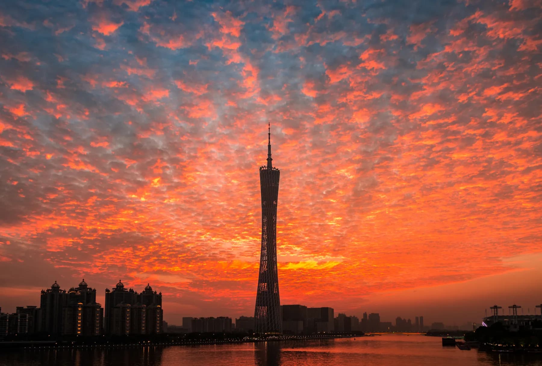 Canton Tower and the Guangzhou skyline beneath a vivid sunset beside the Pearl River