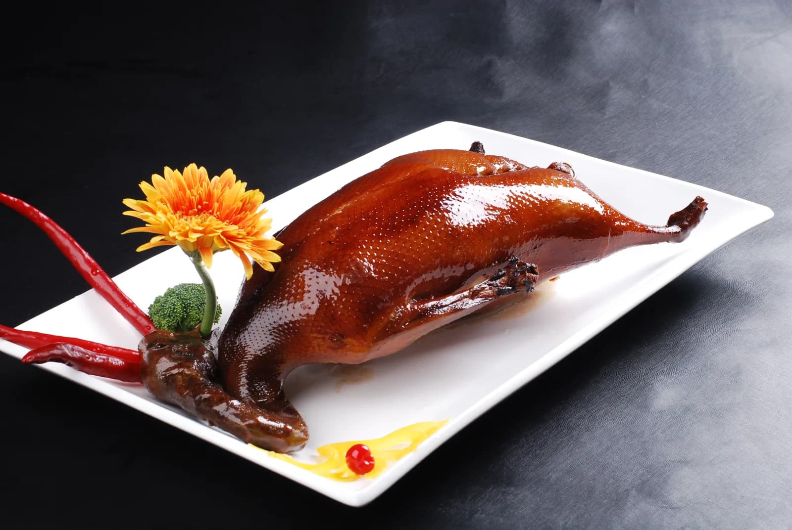 Whole Cantonese roast goose with glossy mahogany skin on a white platter