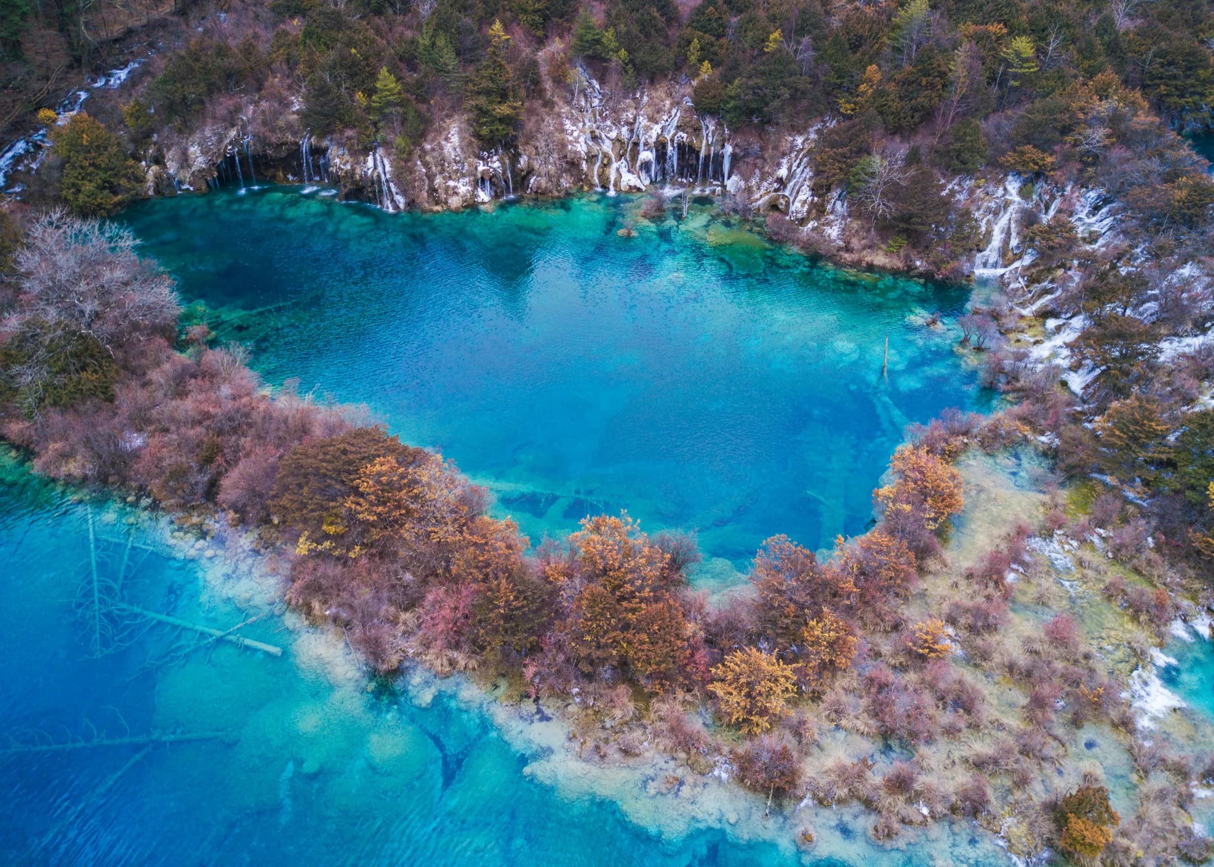 Travel to Jiuzhaigou for intensely blue lakes surrounded by autumn forest