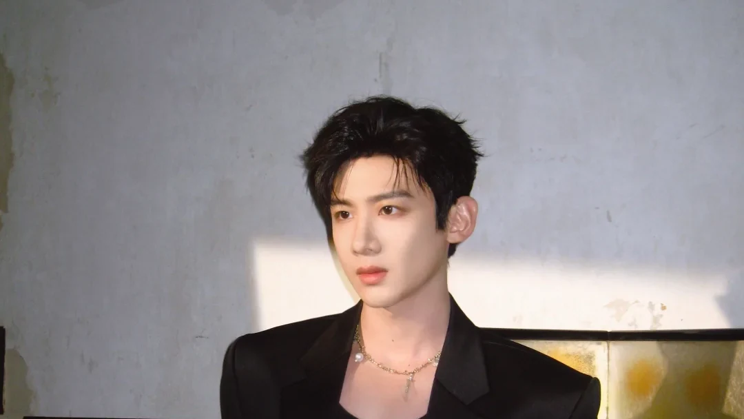 Bai Jingting in a black suit under hard window light in a 2026 official studio portrait