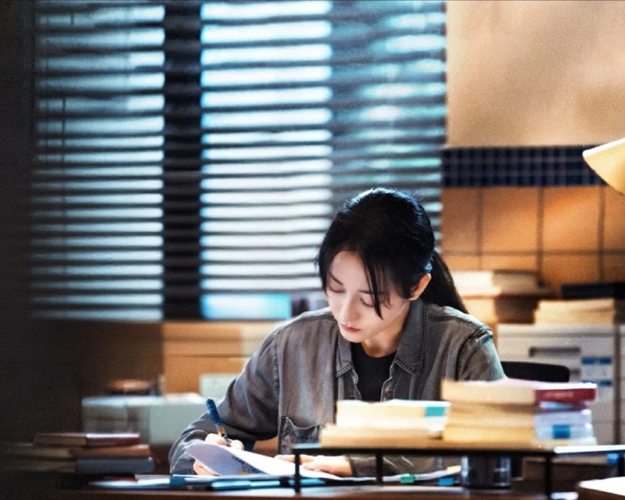 Dilraba Dilmurat as Deng Yan working through case material in Sword Rose