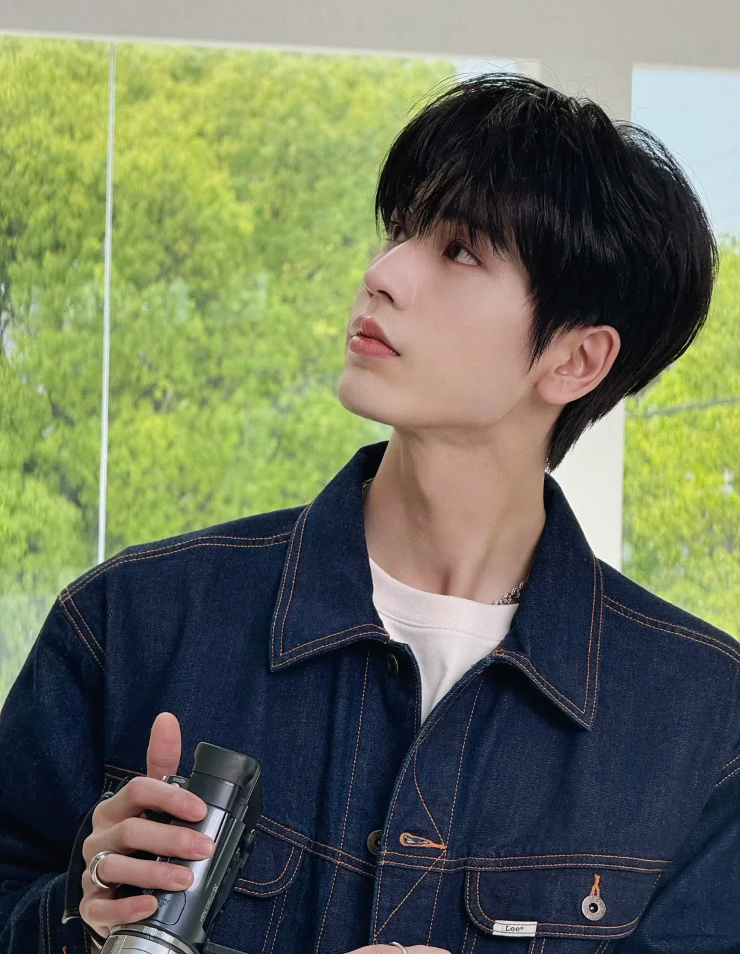 Zhang Linghe in a dark denim jacket holding a small camera in an August 2026 official portrait