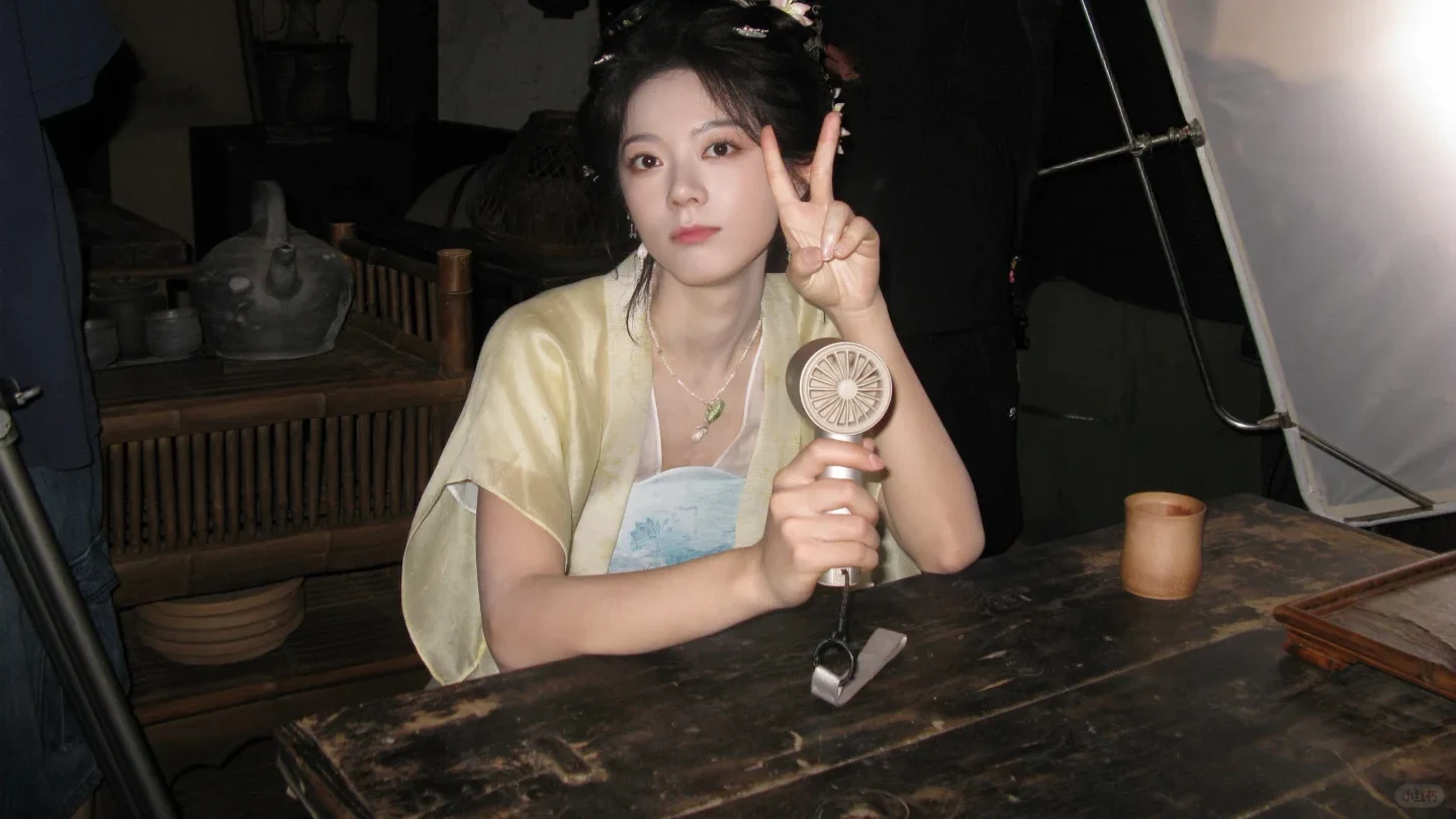 Zhao Jinmai in historical costume holding a small fan between takes in Jiangnan