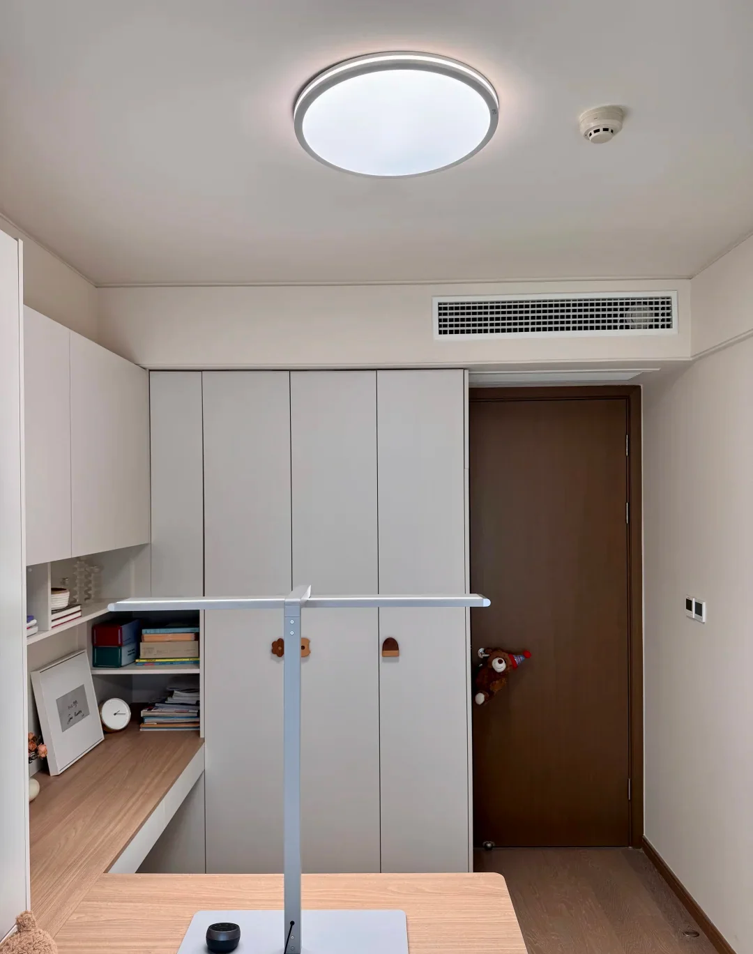 A small bedroom viewed from inside, showing the door, full-height storage and a narrow route beside the bed