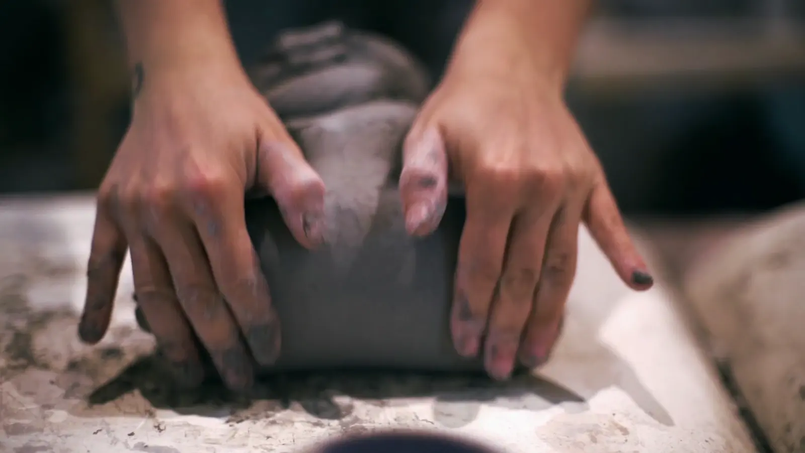 A ceramic maker wedging a block of clay to even its moisture and working consistency