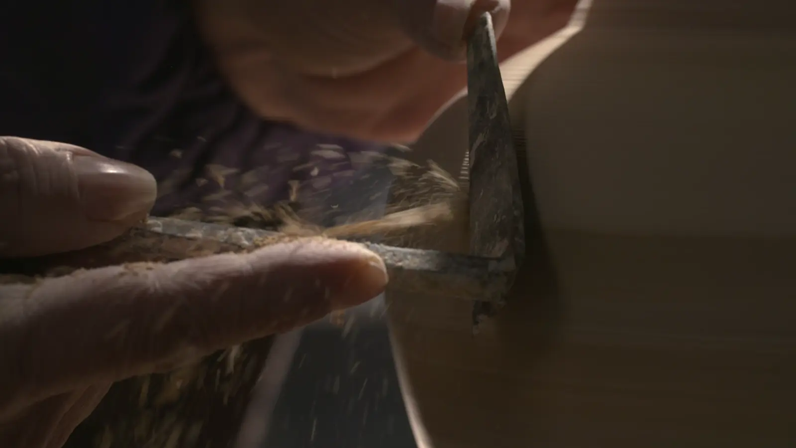 A ceramic foot being trimmed with a metal tool while the vessel turns on the wheel