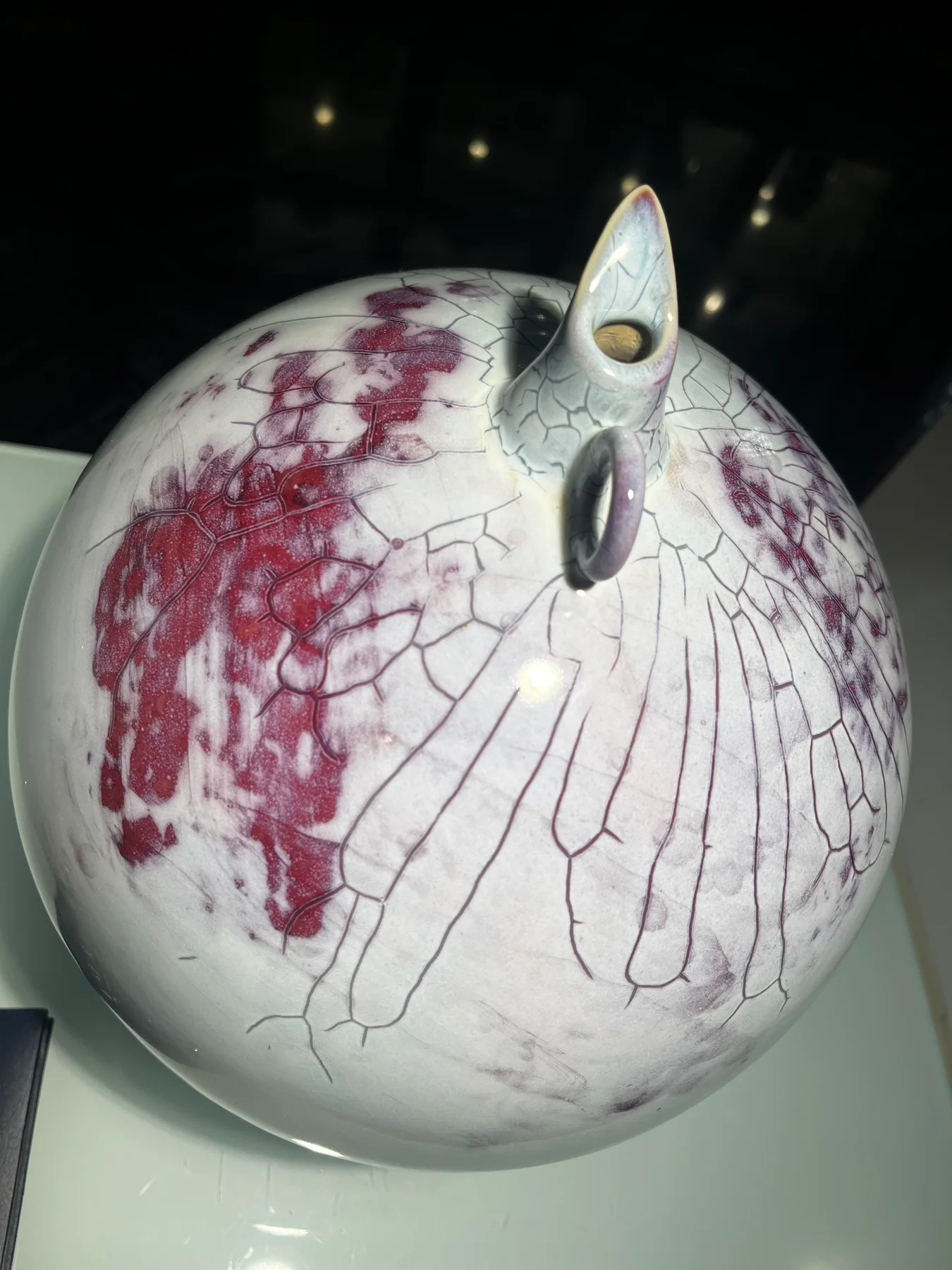 White rounded bird-shaped ceramic vessel with purple glaze movement and a small upward opening
