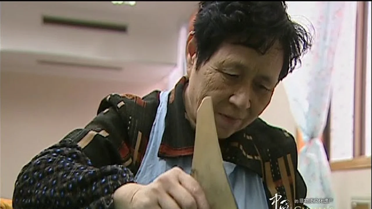 Chinese fan artisan shaping a wooden fan component in an official craft video