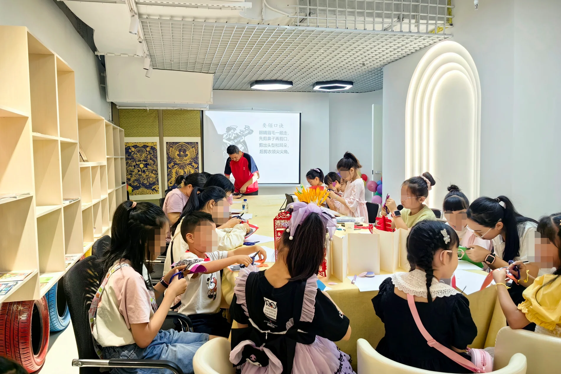 Shen Songbai teaching Chinese paper cutting to several students around a shared worktable