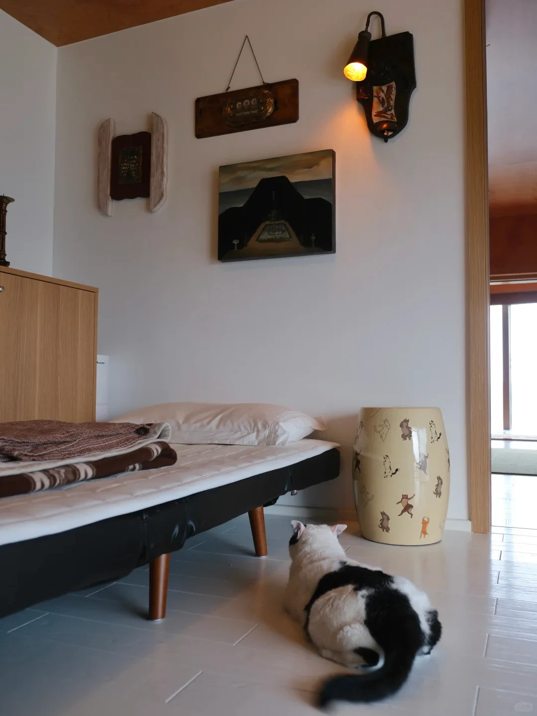 A ceramic drum stool used beside a low guest bed, with the surrounding floor left visible