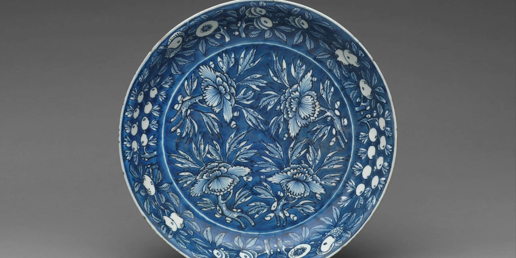 A Chinese porcelain dish with flowering branches reserved against a cobalt-blue ground