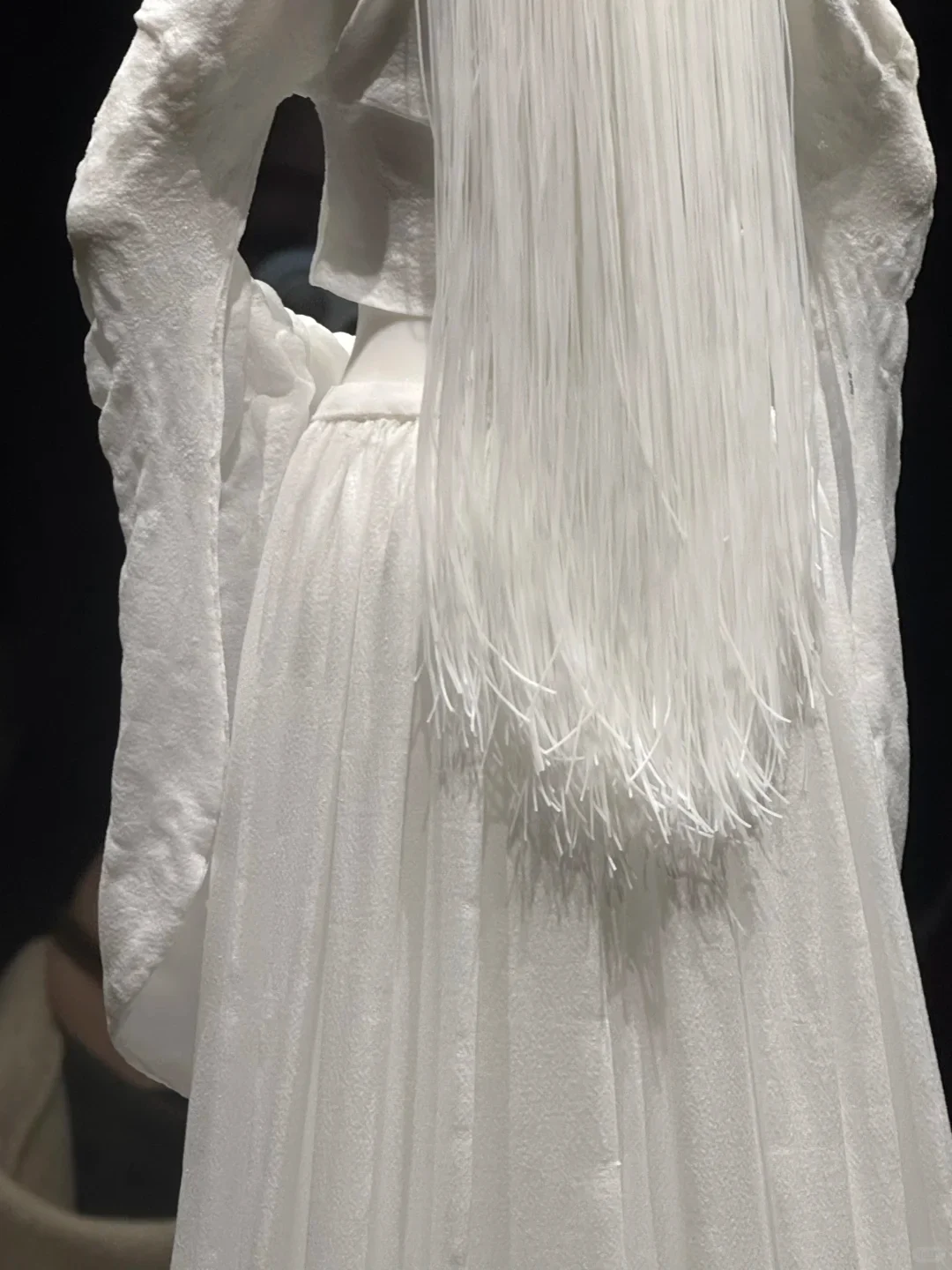 Close view of the pleated dress and hanging sleeves on a contemporary white porcelain figure