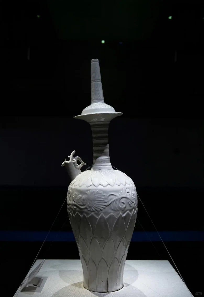 Ding ware dragon-head purification bottle displayed upright, with carved lotus petals and a projecting side spout