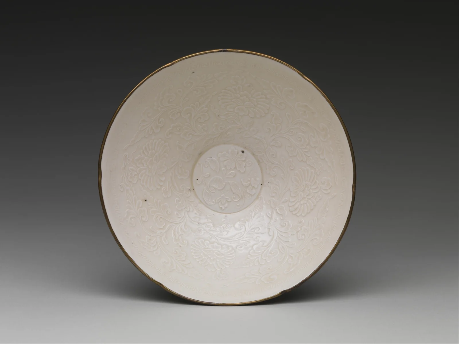 Interior of a Ding ware bowl showing mold-impressed peonies beneath ivory glaze