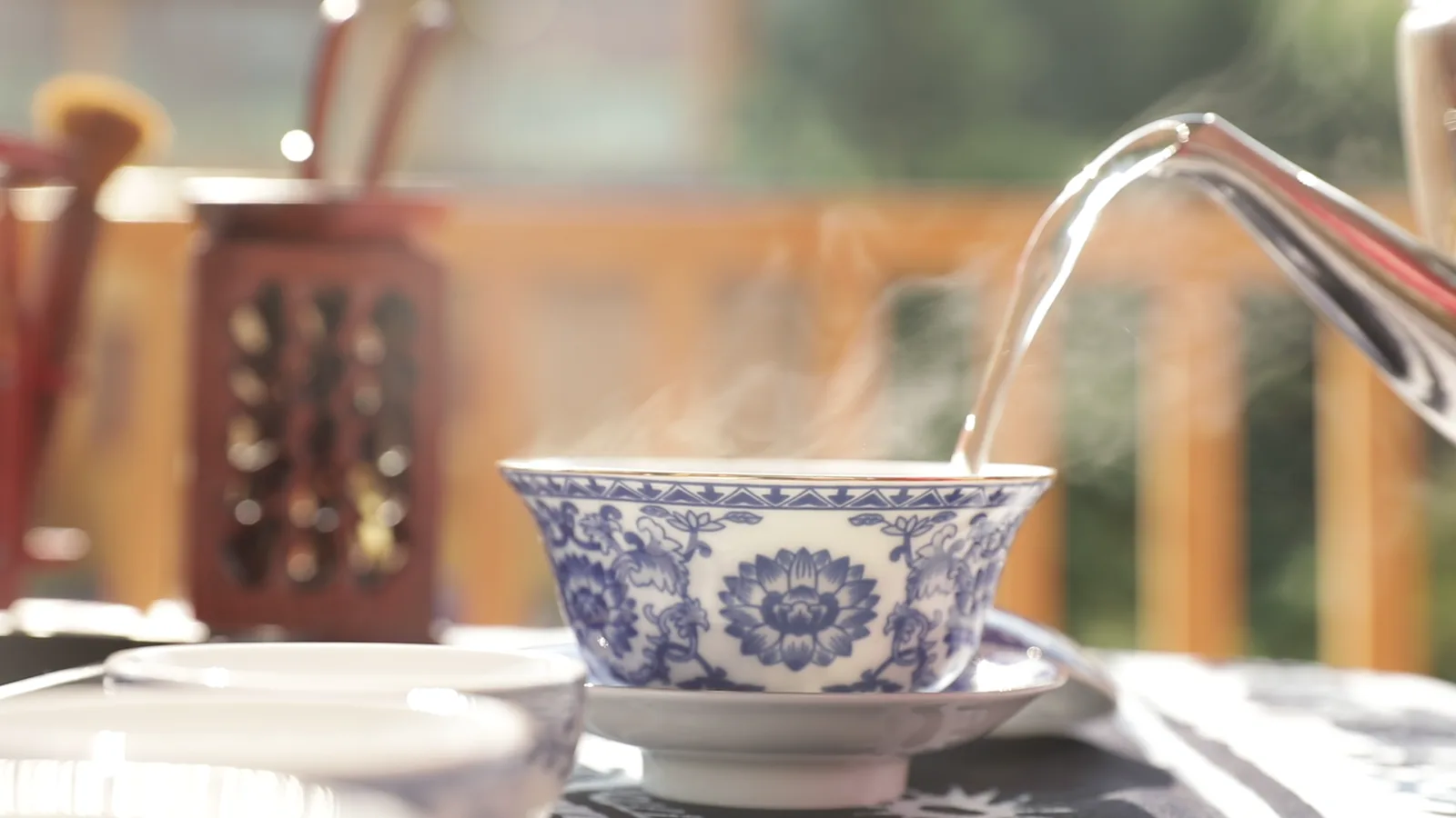 Hot water pouring into a blue-and-white porcelain tea bowl during everyday use