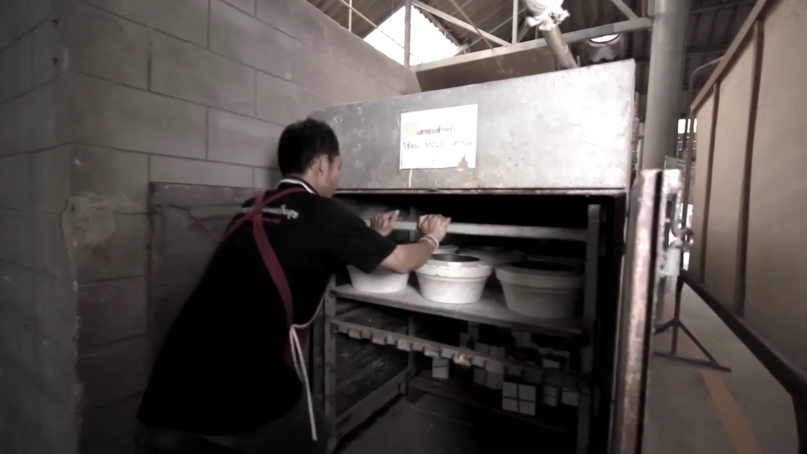 Ceramic workers loading pale vessels onto kiln shelves before high-temperature firing