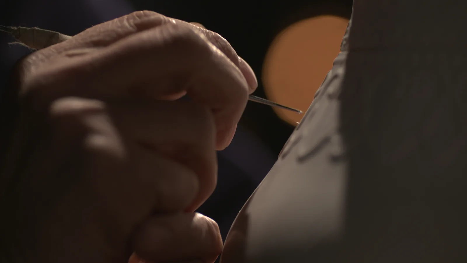 A craftsperson carving relief into a porcelain body before glaze and firing