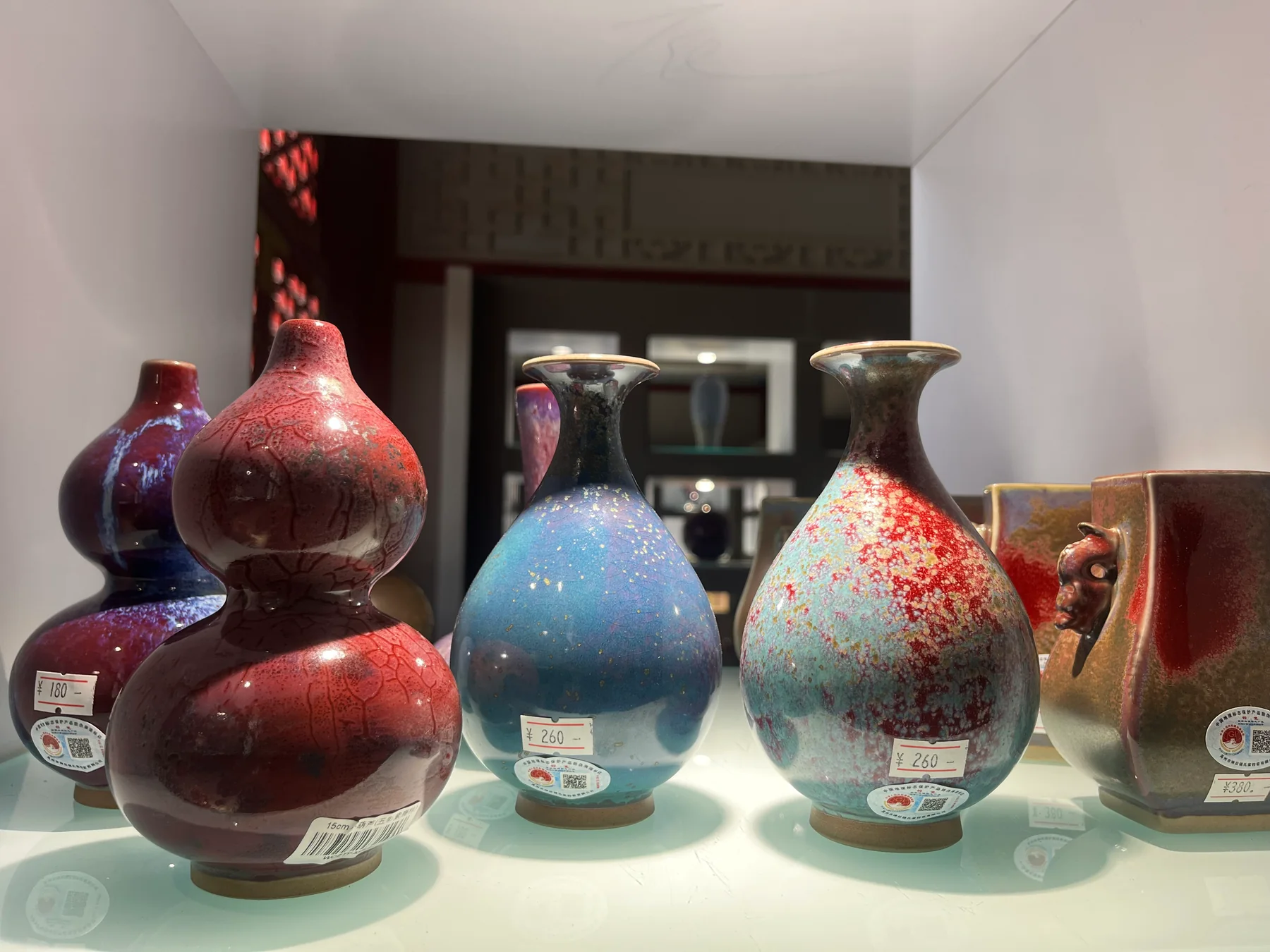 Several contemporary Jun-style vessels displayed together in blue, red and purple glaze families