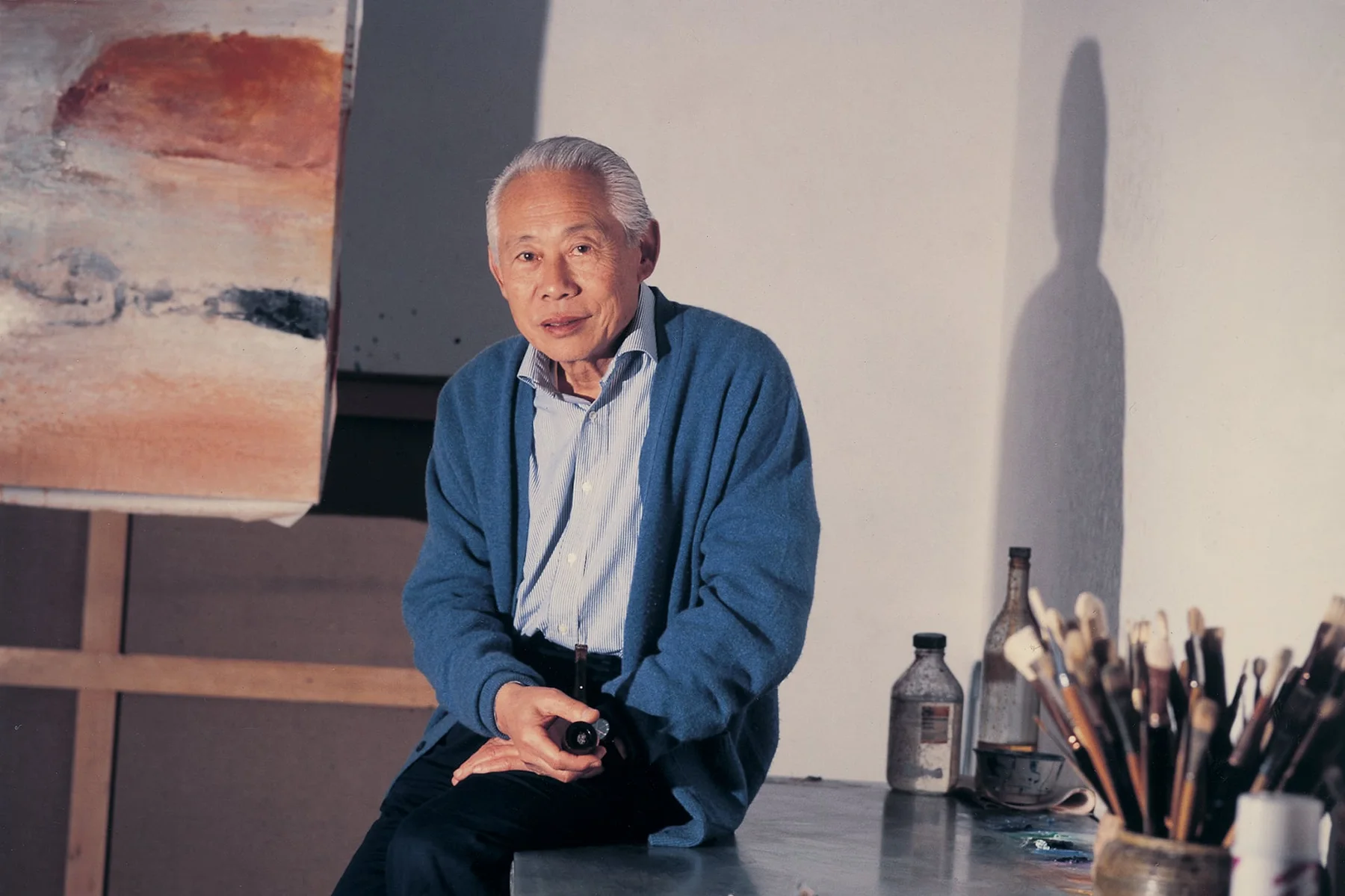 Zao Wou-Ki seated among brushes, pigments and paintings in his Paris studio in 1995