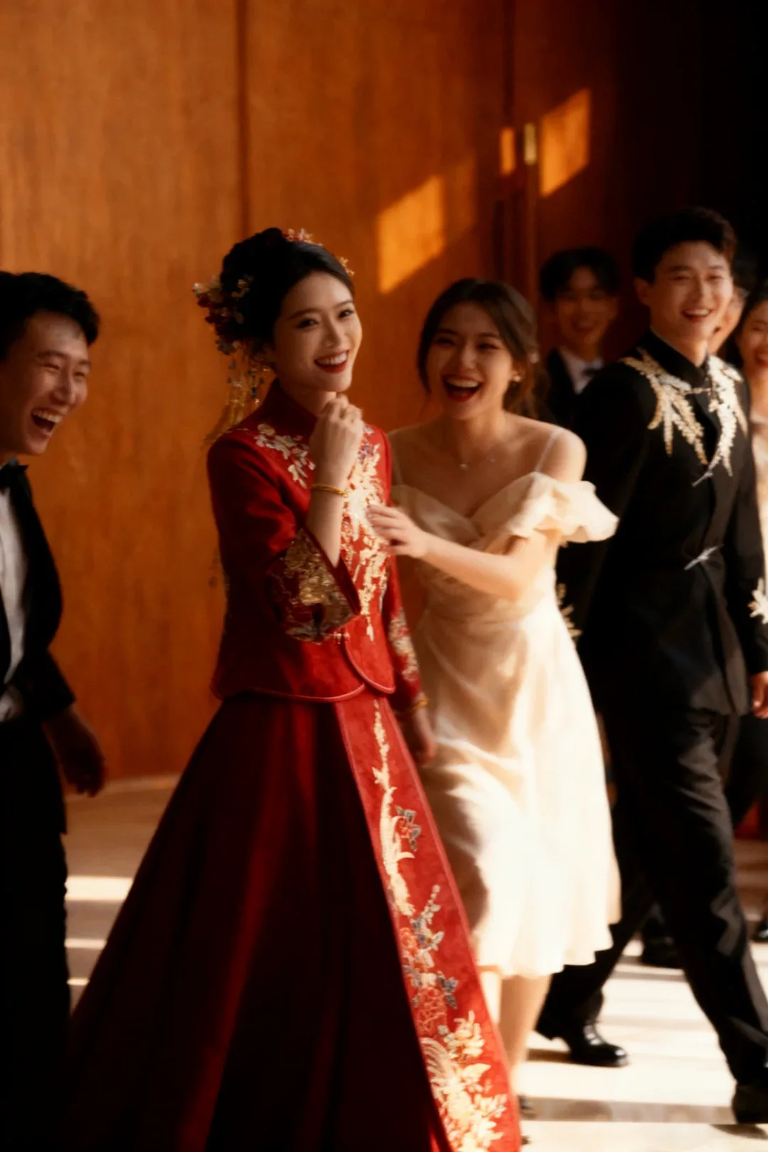 no-caption A bride and groom in coordinated red and black Chinese wedding clothing laughing among friends in Western formalwear