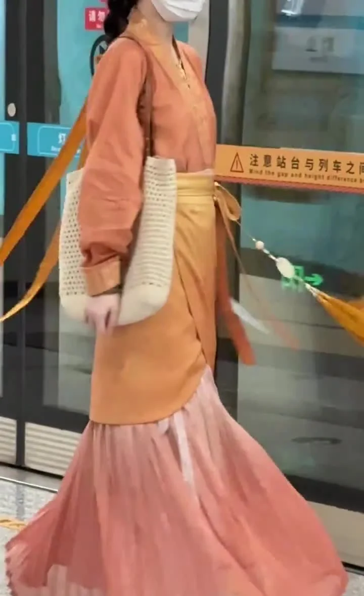Front view of a layered Hanfu outfit moving beside metro platform doors