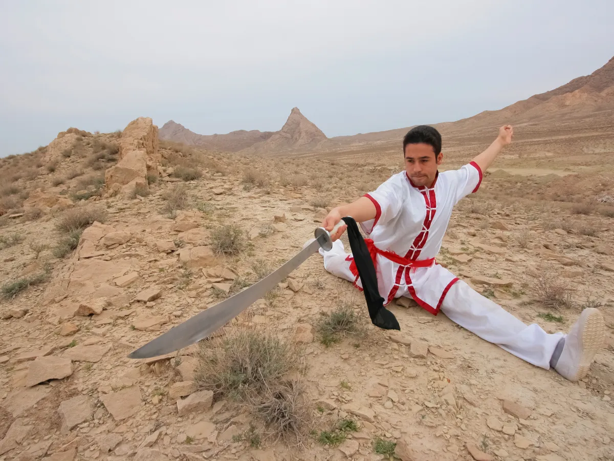 A Chinese wushu athlete holding a straight-sword stance, showing sport as trained repetition before spectacle
