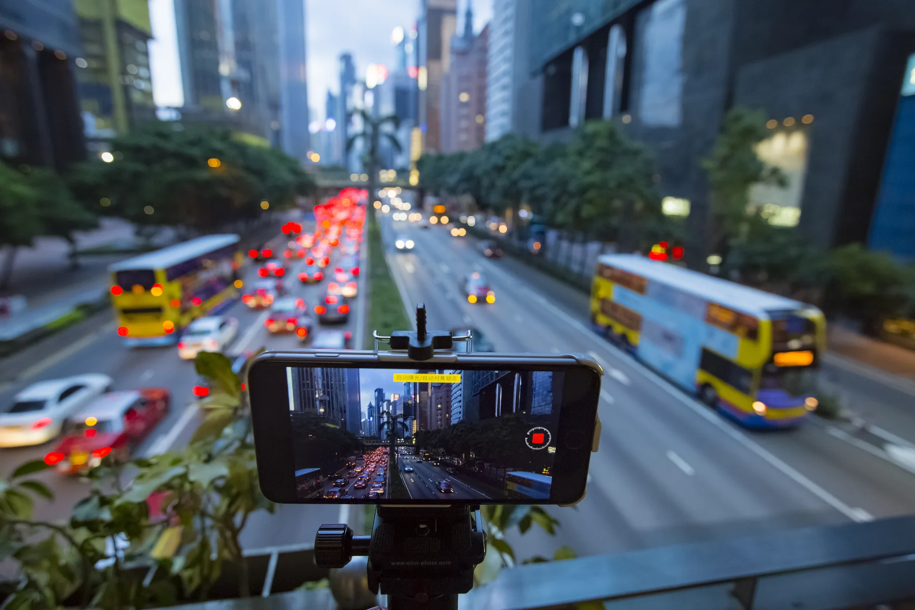 A smartphone recording Hong Kong traffic, showing the screen between an urban event and its digital circulation