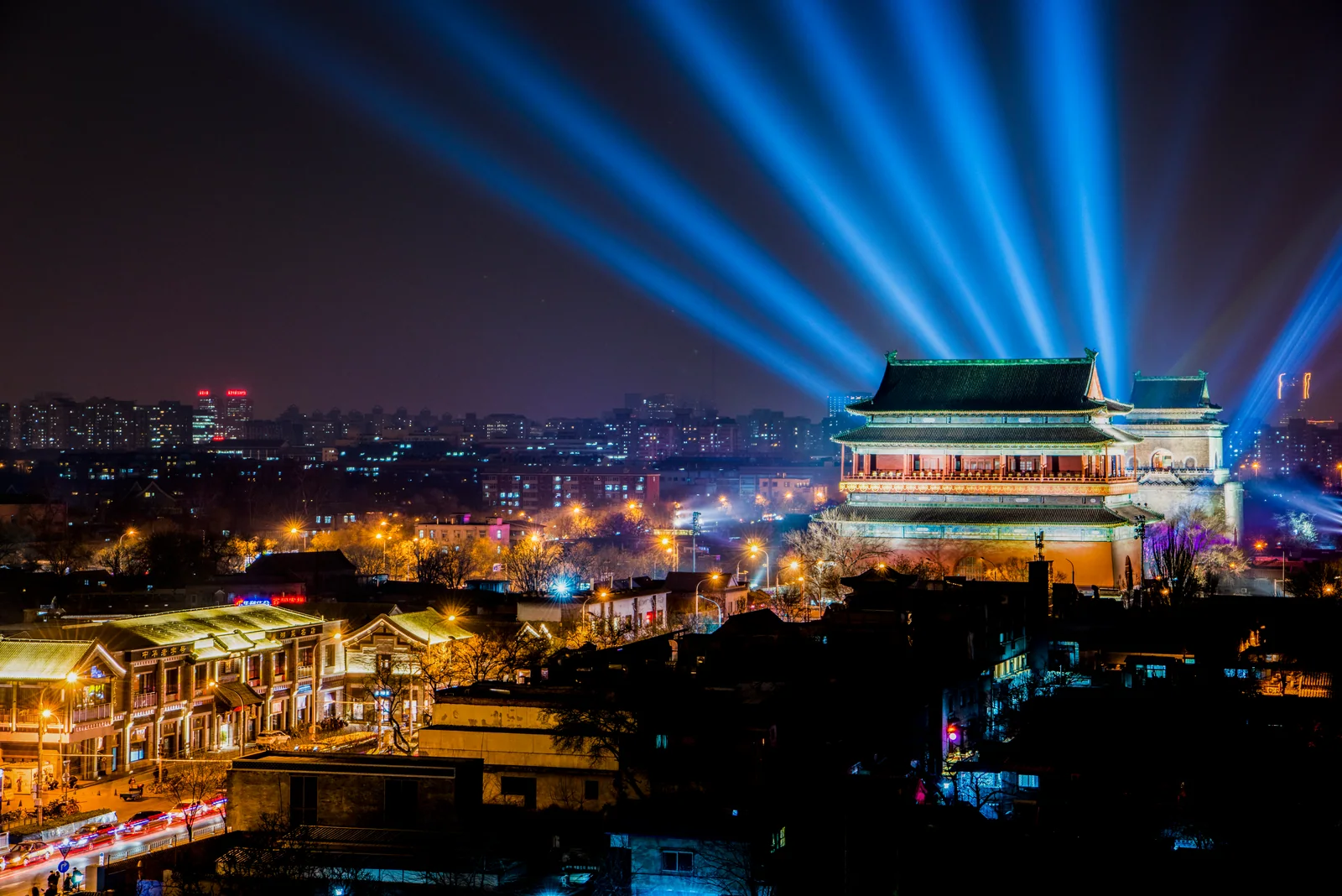 Beijing Drum Tower illuminated at night as neighborhood streets continue around it