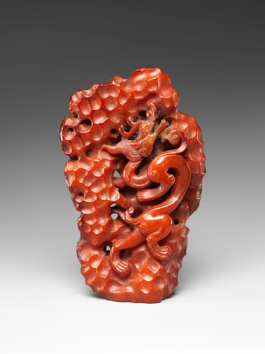 Fourteenth-century carved dragon climbing through a porous rock