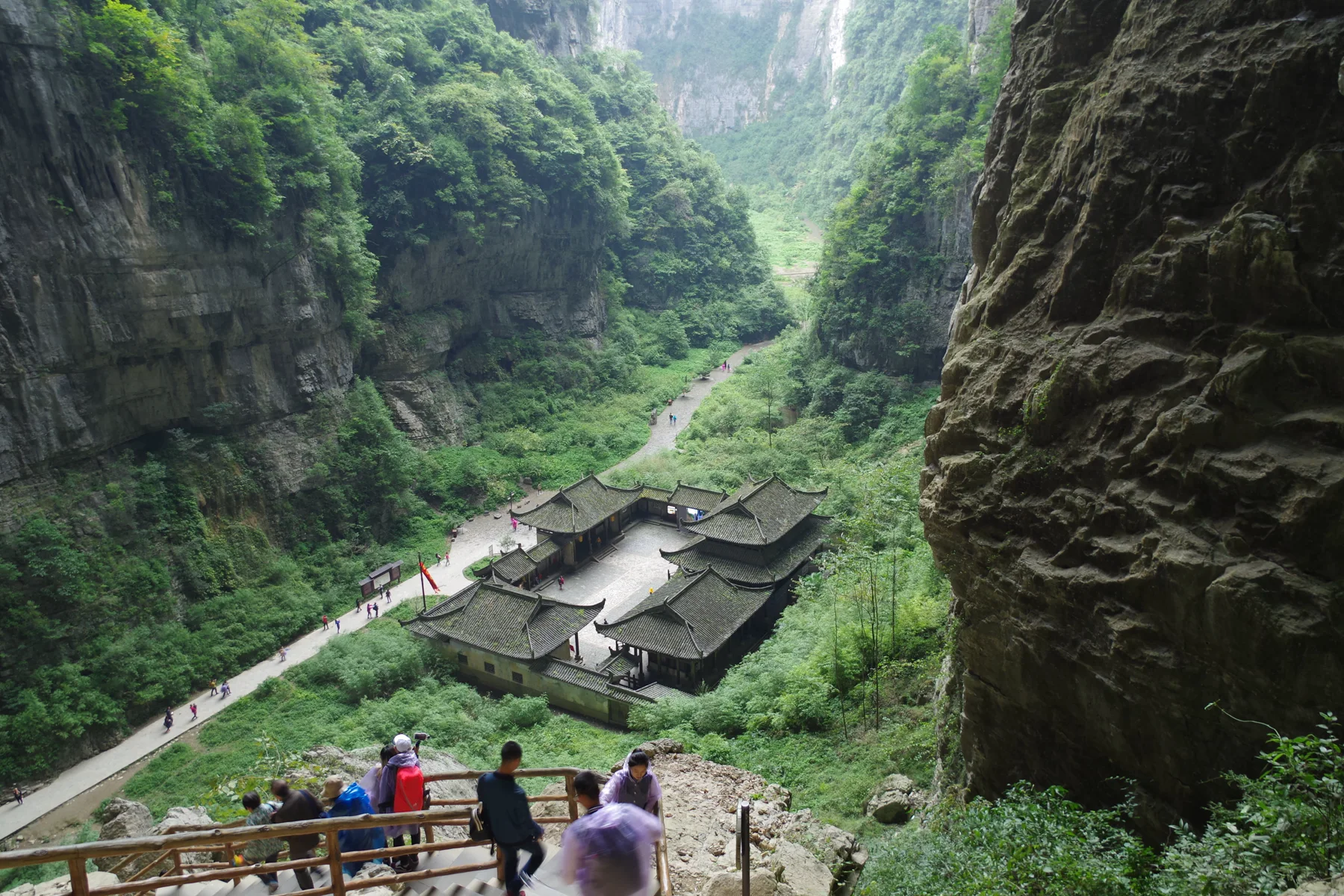A path and traditional-style building complex inside a steep Wulong karst gorge