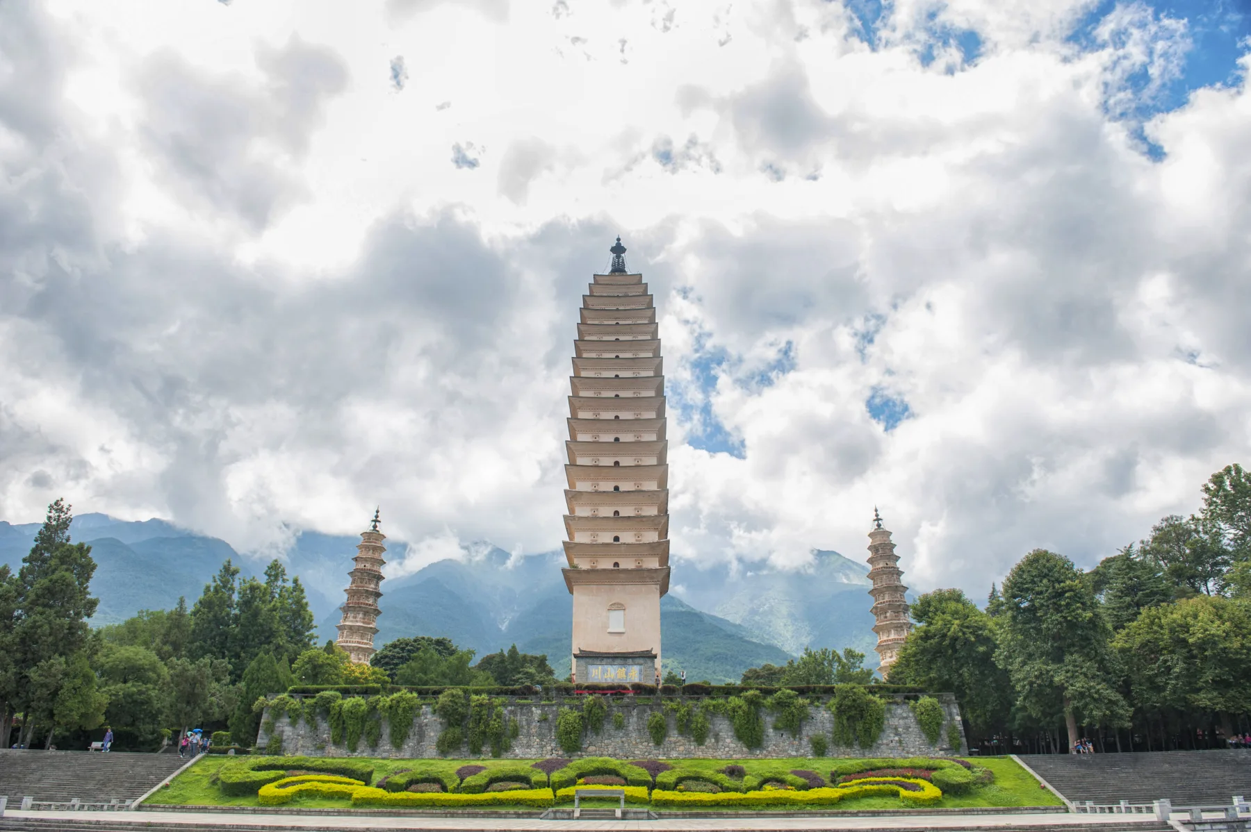 The Three Pagodas standing before Cangshan beneath broken clouds