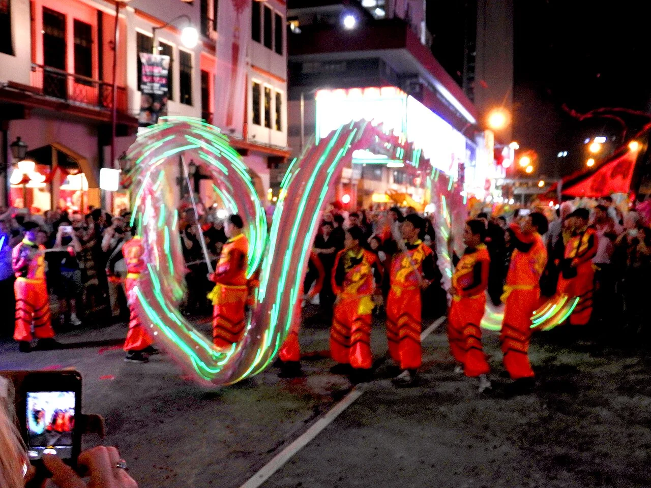 Illuminated Chinese dragon dance body forming a wave above a line of performers