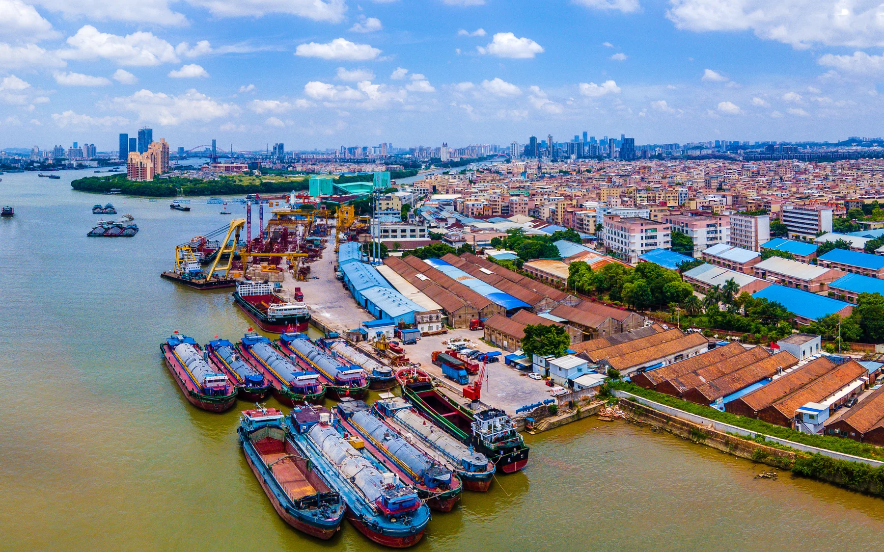 Working barges and the dense Pearl River shoreline in Guangzhou