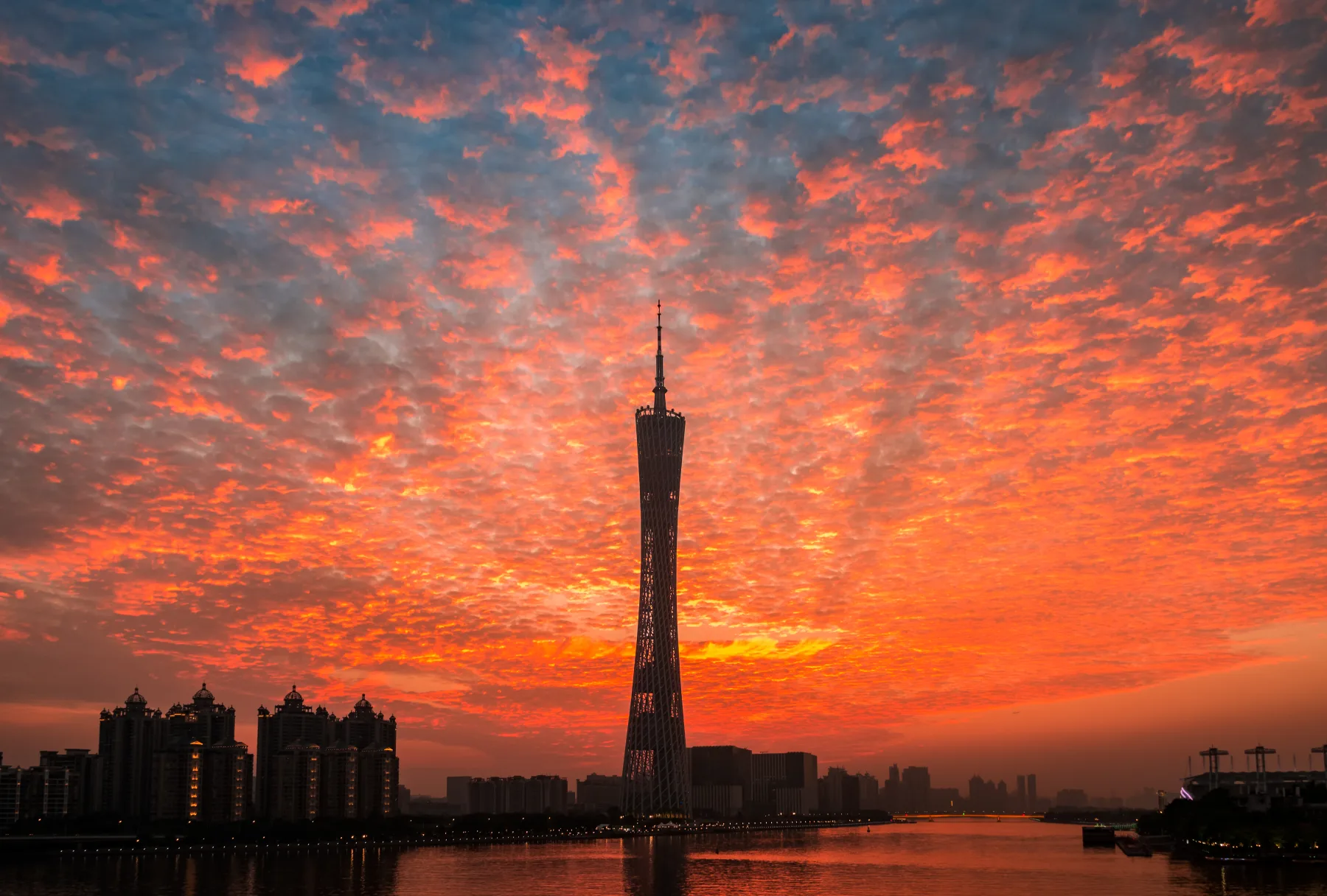 Canton Tower and the Guangzhou skyline beneath a vivid sunset beside the Pearl River