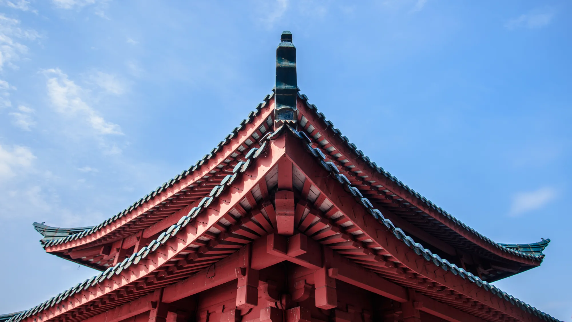 Red timber roof structure of Cui Guang Pavilion beneath a bright sky