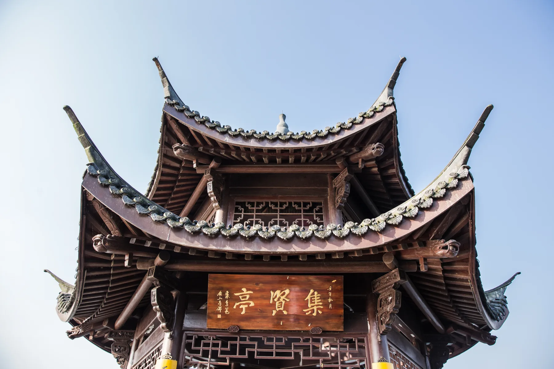 Layered timber roof and eaves of Jixian Pavilion against a clear sky