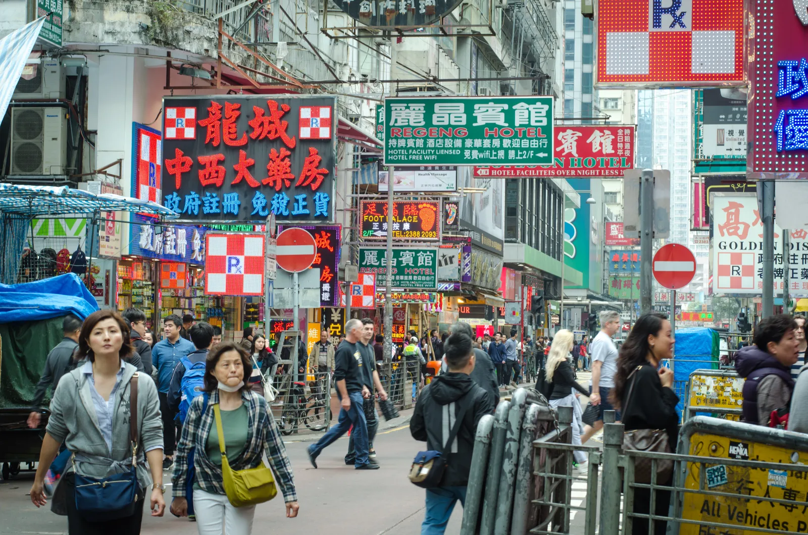 Crowded Mong Kok street with pedestrians, layered signs, shops and guesthouses