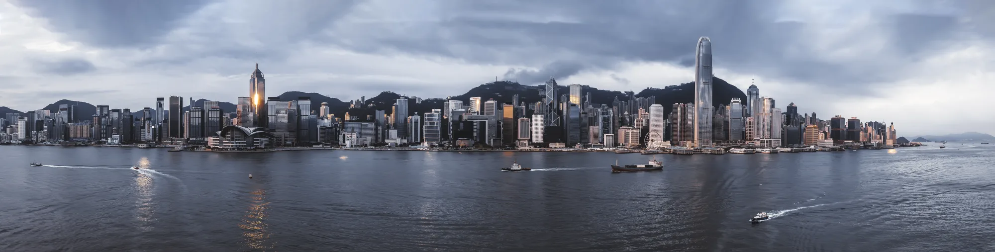 Victoria Harbour at sunrise with boats moving between Kowloon and Hong Kong Island
