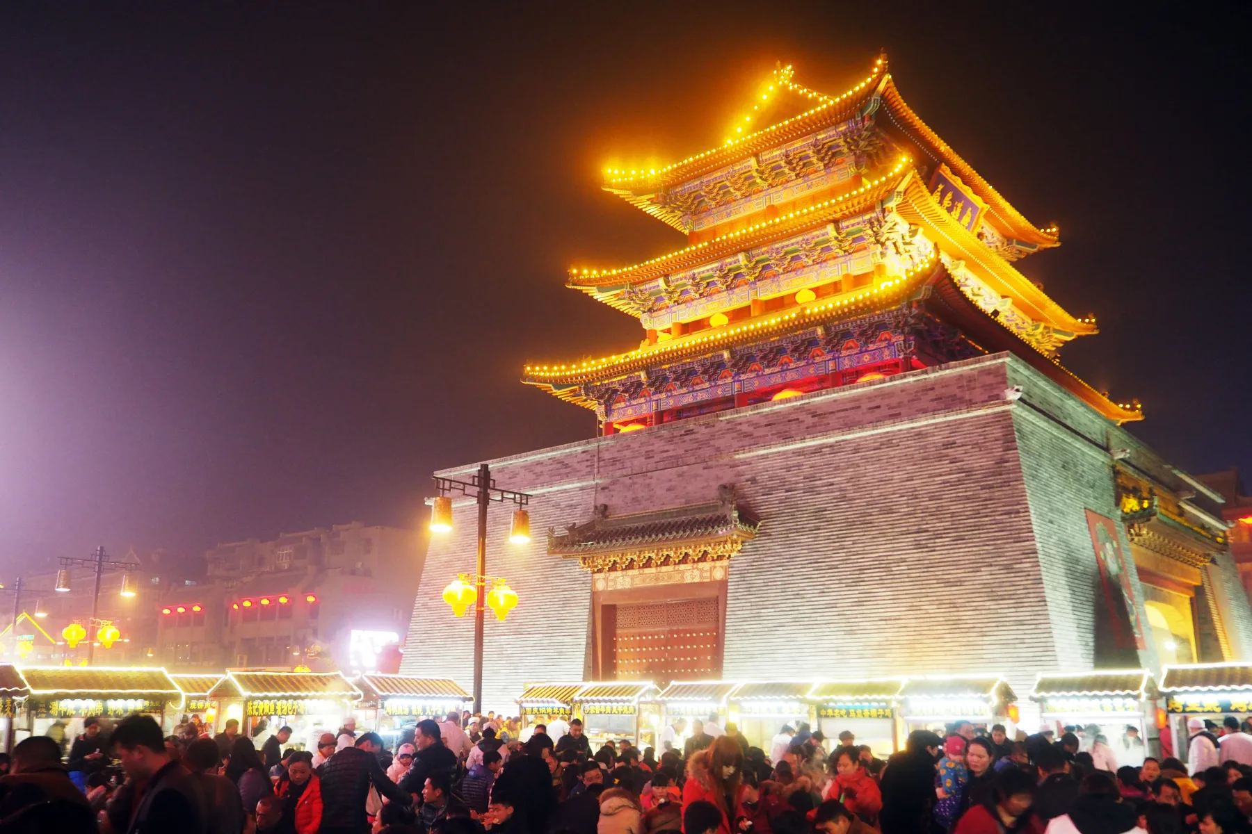 Crowds gathering around the illuminated Drum Tower at night