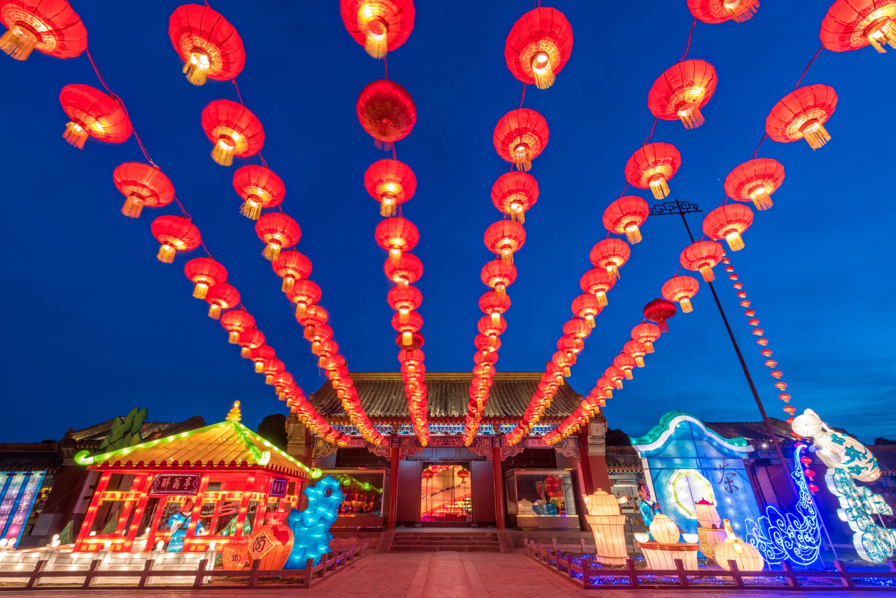 Rows of red lanterns leading toward an illuminated festival gate in Kaifeng