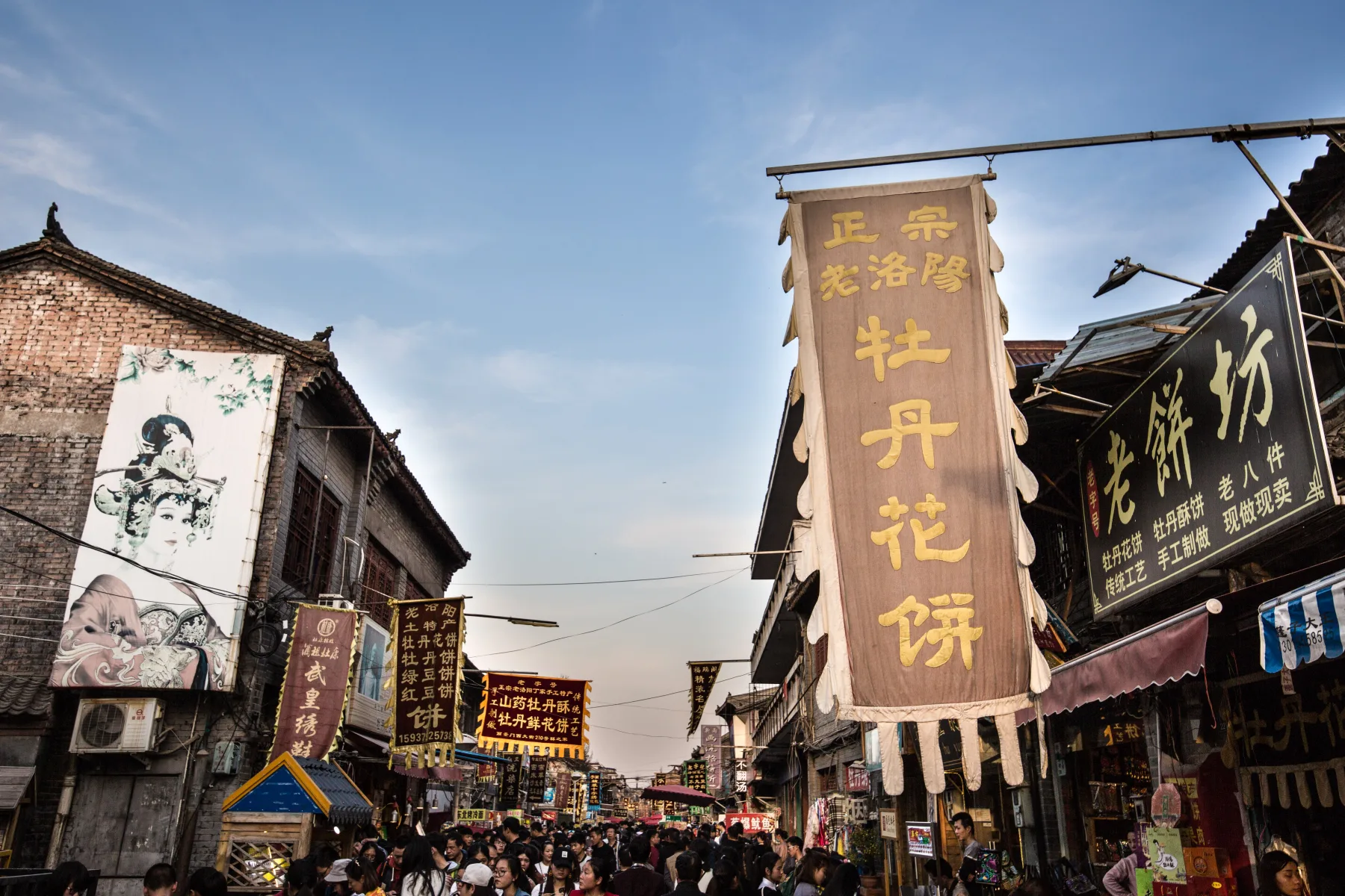 Visitors and shopfronts along a busy commercial street in Luoyang's old city