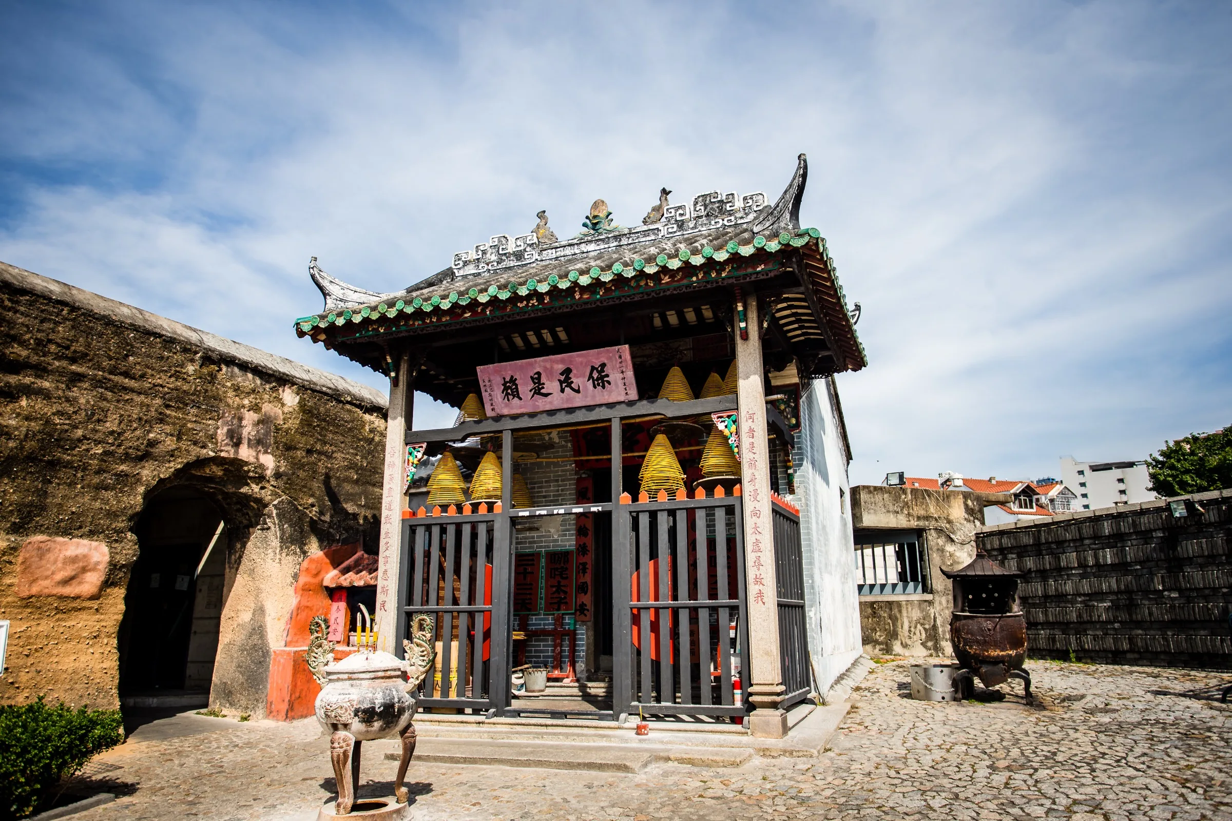 Small Chinese temple beside old stone walls reflecting Macau culture