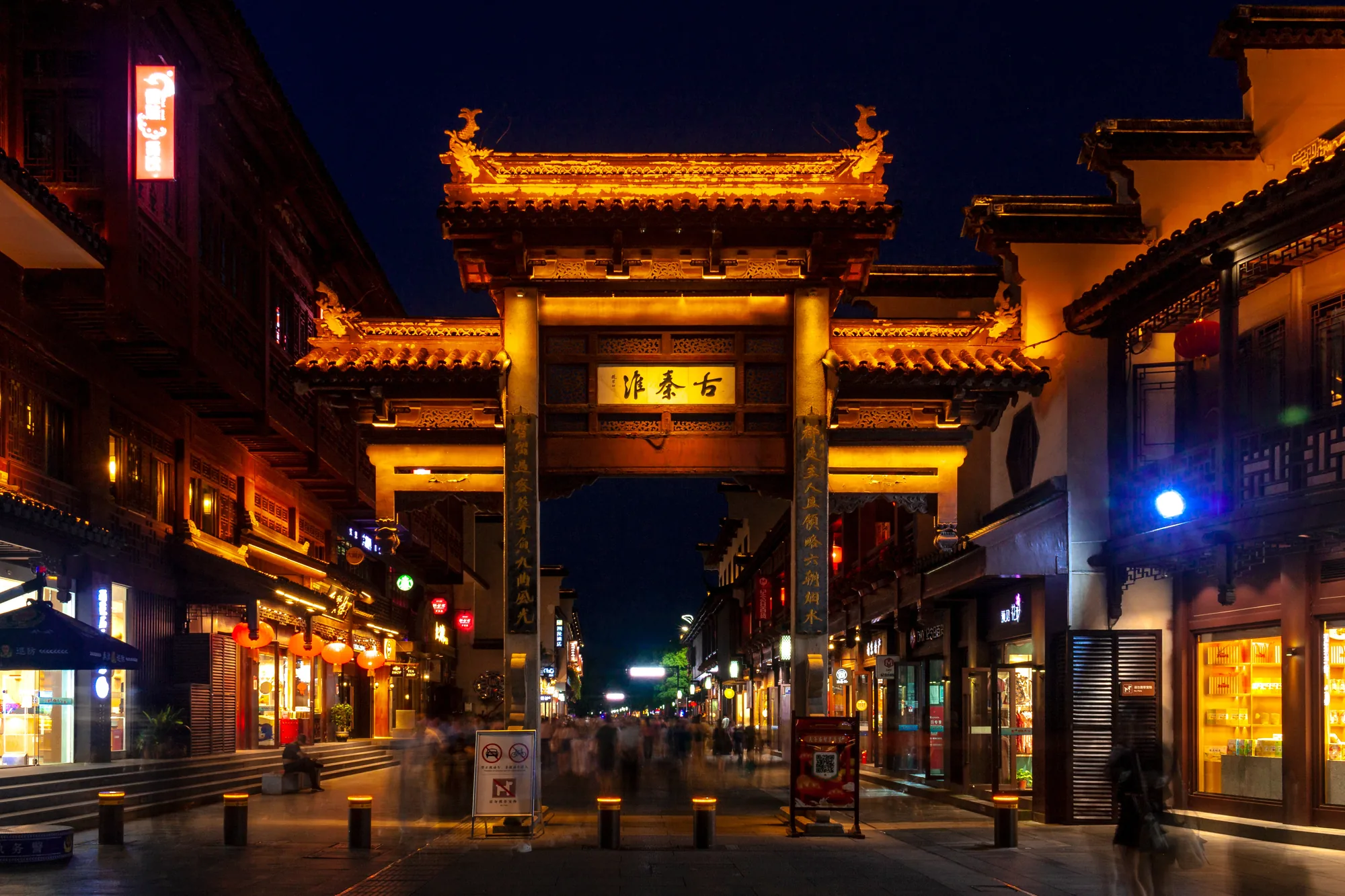 Illuminated archway and dense evening crowds in the Confucius Temple district