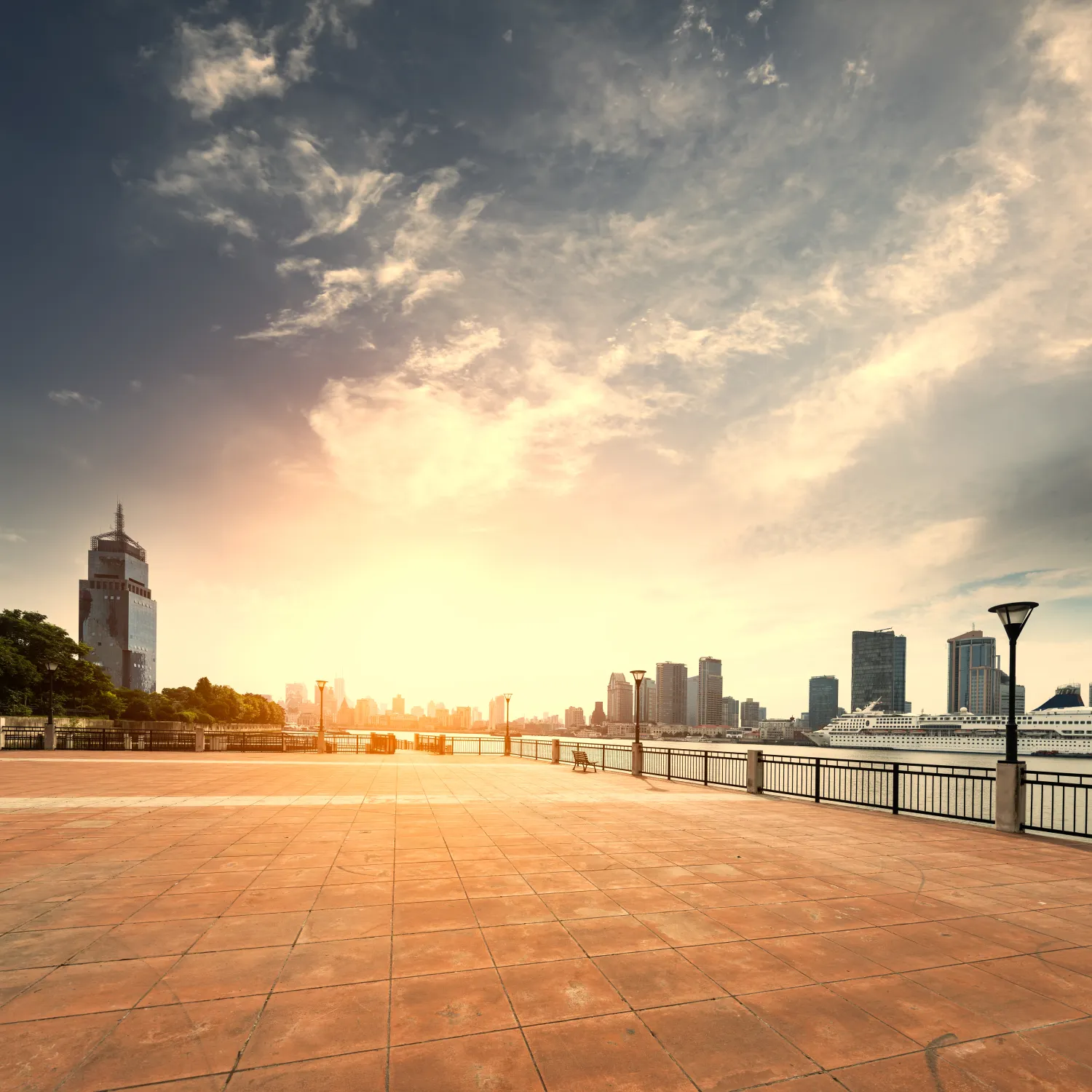 A broad Shanghai riverfront promenade at sunrise with open public space beside the Huangpu River