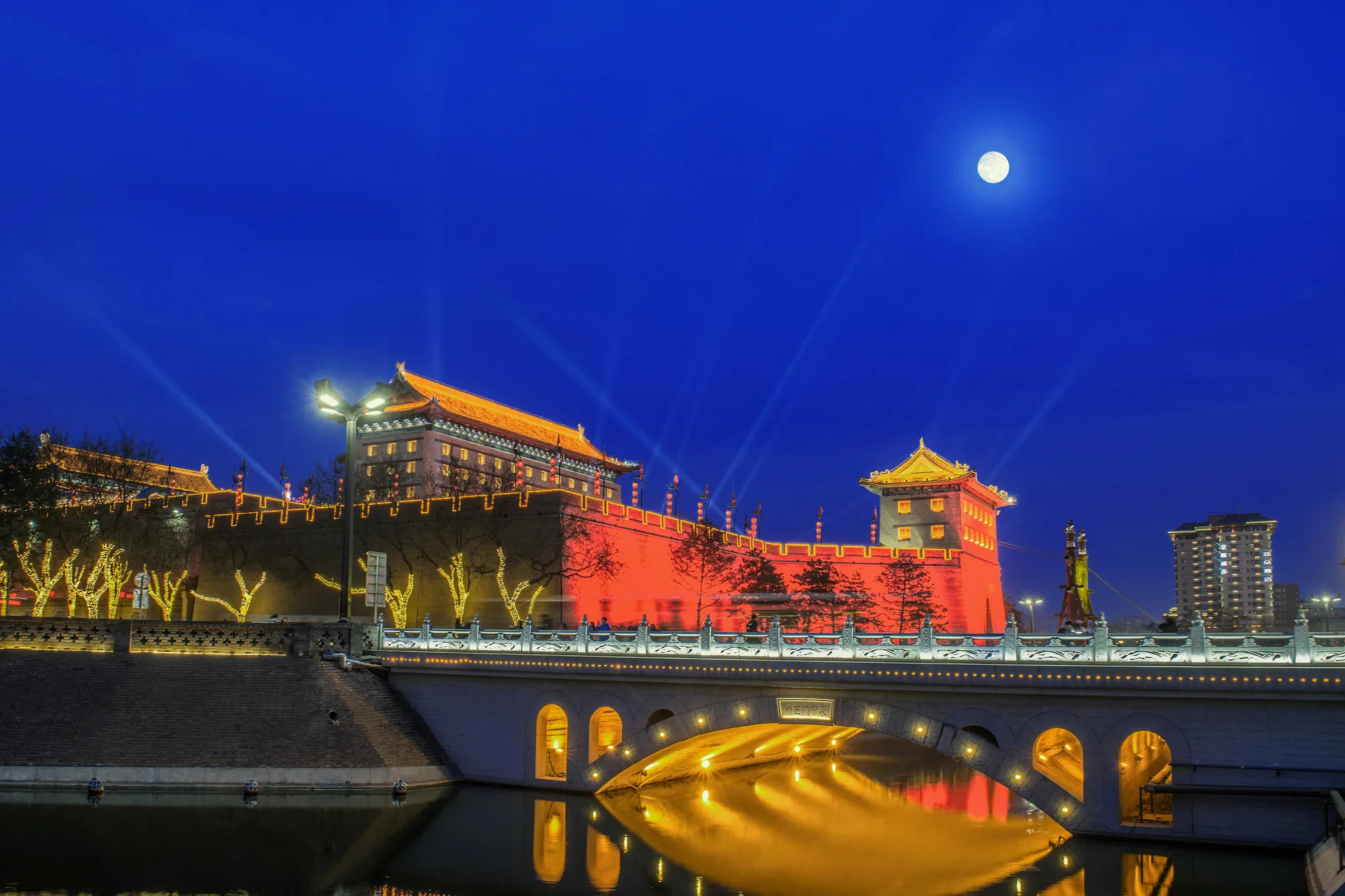 Illuminated walls, towers and moat reflected at night in central Xi'an