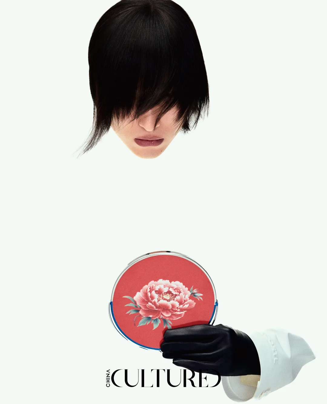 A close editorial composition of a hand holding a peony object beneath a face obscured by a precise black haircut