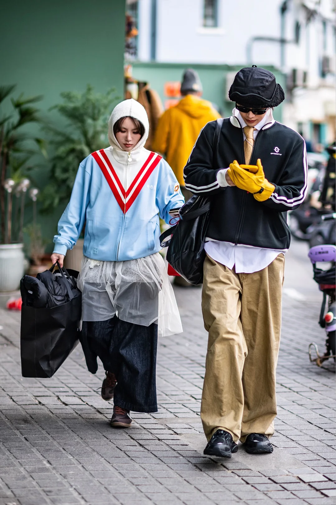 Two Shanghai pedestrians combining a pale blue sport jacket, sheer layer, broad khaki trousers and bright yellow gloves