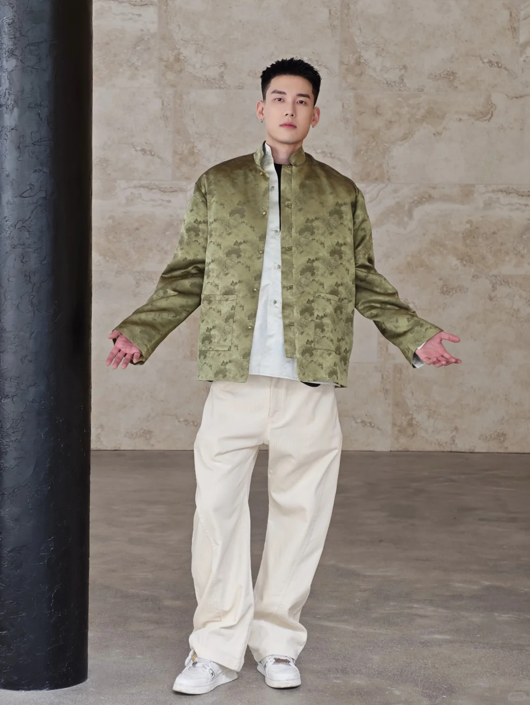 A model in an olive jacquard jacket with a standing collar, straight body and cream wide trousers