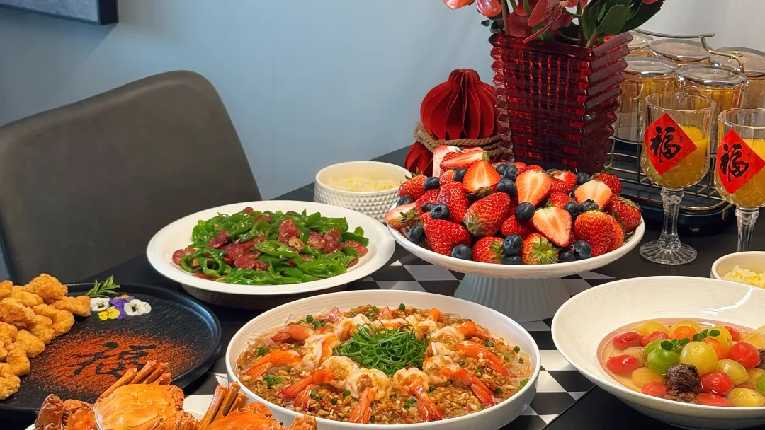 A contemporary Chinese New Year table set with crab, shrimp, fruit, meat, rice bowls and red fu decorations