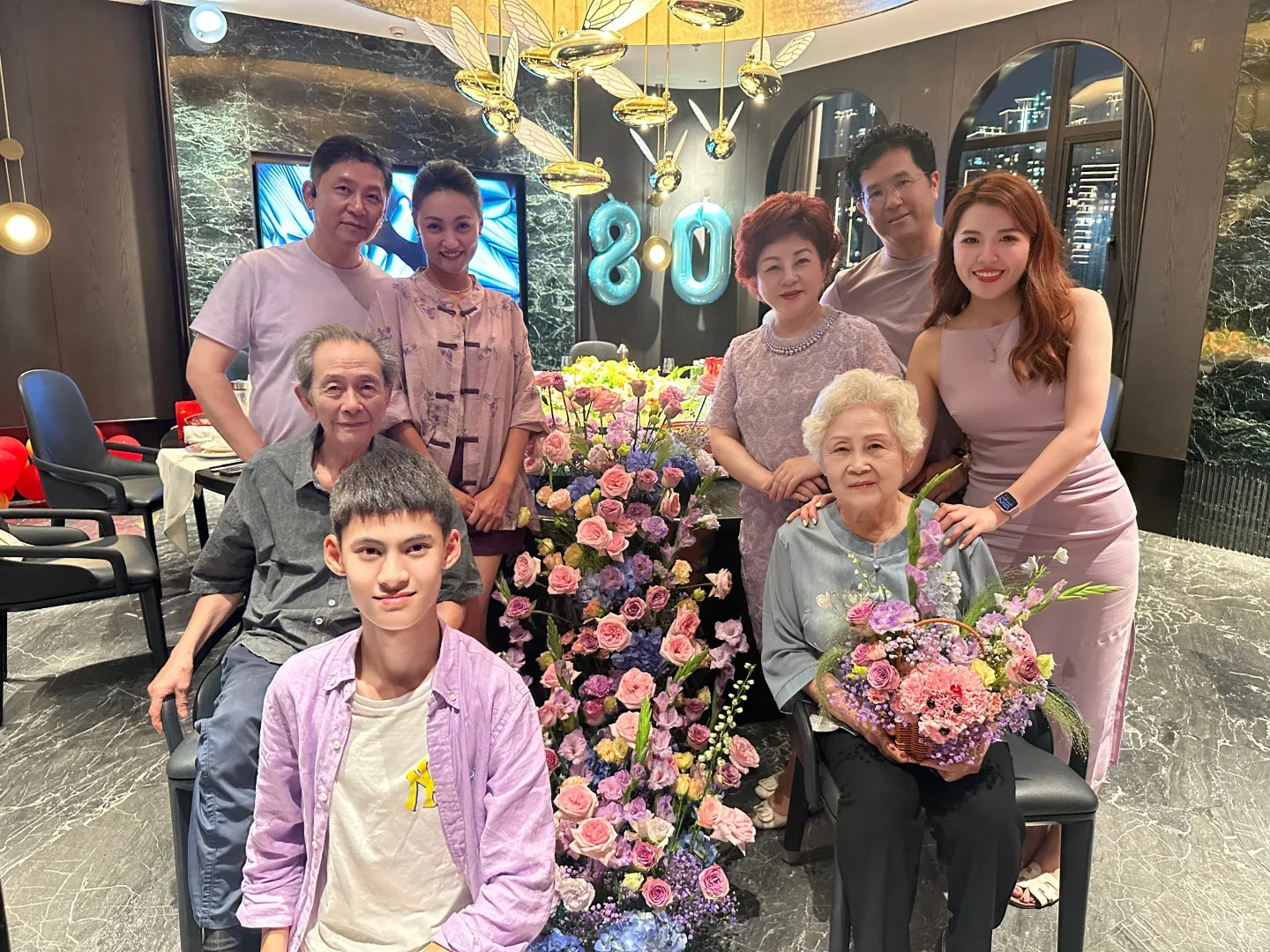 Three generations gathered around an 80-year-old elder at a family celebration